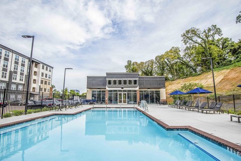 A large swimming pool in front of a building with a black fence around it.