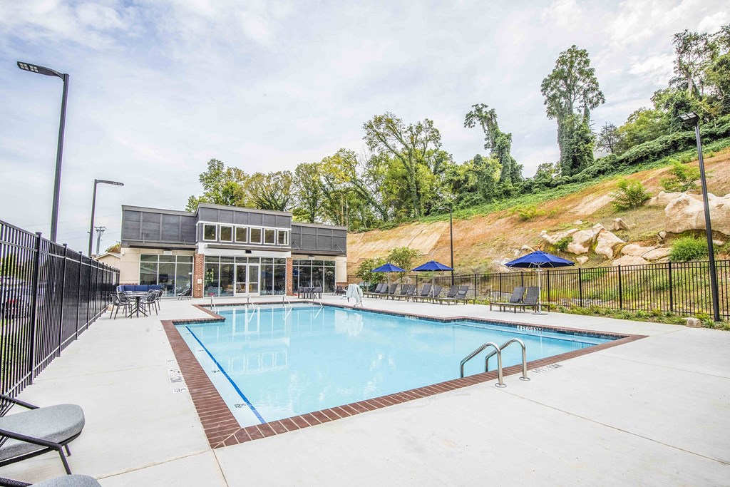 A large outdoor swimming pool with a black fence and a building in the background.