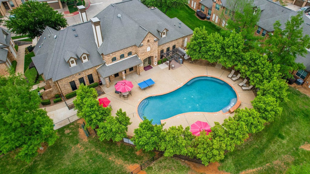 an aerial view of a pool and a house with umbrellas