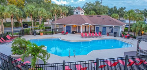 a resort style pool with red chairs and a building with a pool