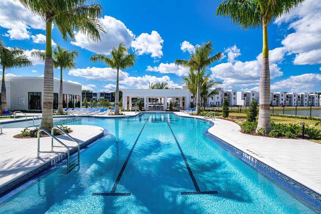 a large swimming pool with palm trees and buildings in the background at Altis Blue Lake, Lake Worth, Florida
