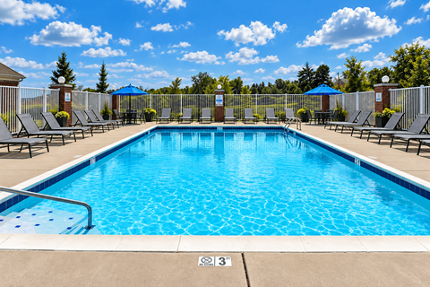 A large outdoor swimming pool surrounded by lounge chairs and umbrellas.