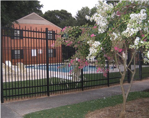 a wrought iron fence with a swimming pool in front of a house