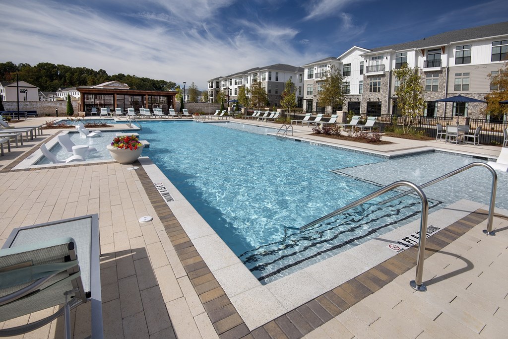 the resort style pool is next to the poolside cabanas and an apartment building