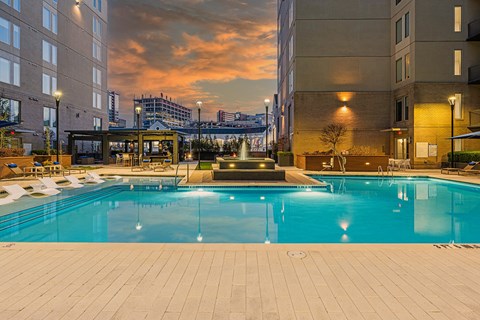 Luxury Apartments For Rent In Atlanta, GA - Venue Brookwood - Saltwater Pool With Spacious Sundeck, Submerged And Poolside Lounge Chairs, And Fountain.