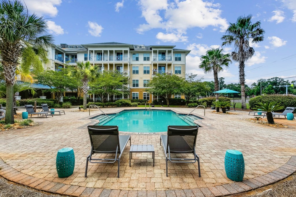 a pool with chairs and a table next to a resort pool