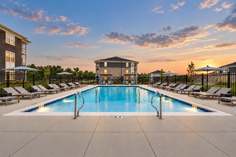 A large swimming pool surrounded by lounge chairs and umbrellas.