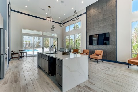 A modern kitchen with a large island and a refrigerator on the left.