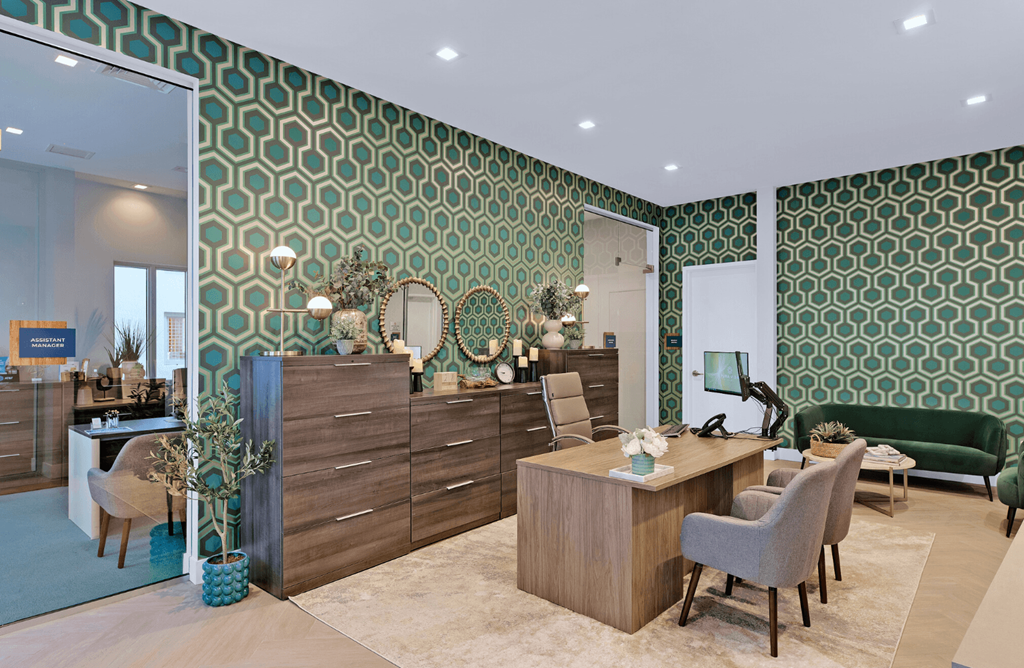 a living room with green wallpaper and a desk with chairs