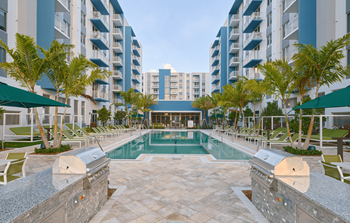 a swimming pool with palm trees in front of an apartment building