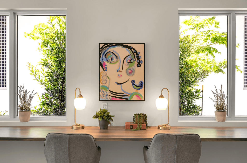 a painting of a woman on a wall next to a desk