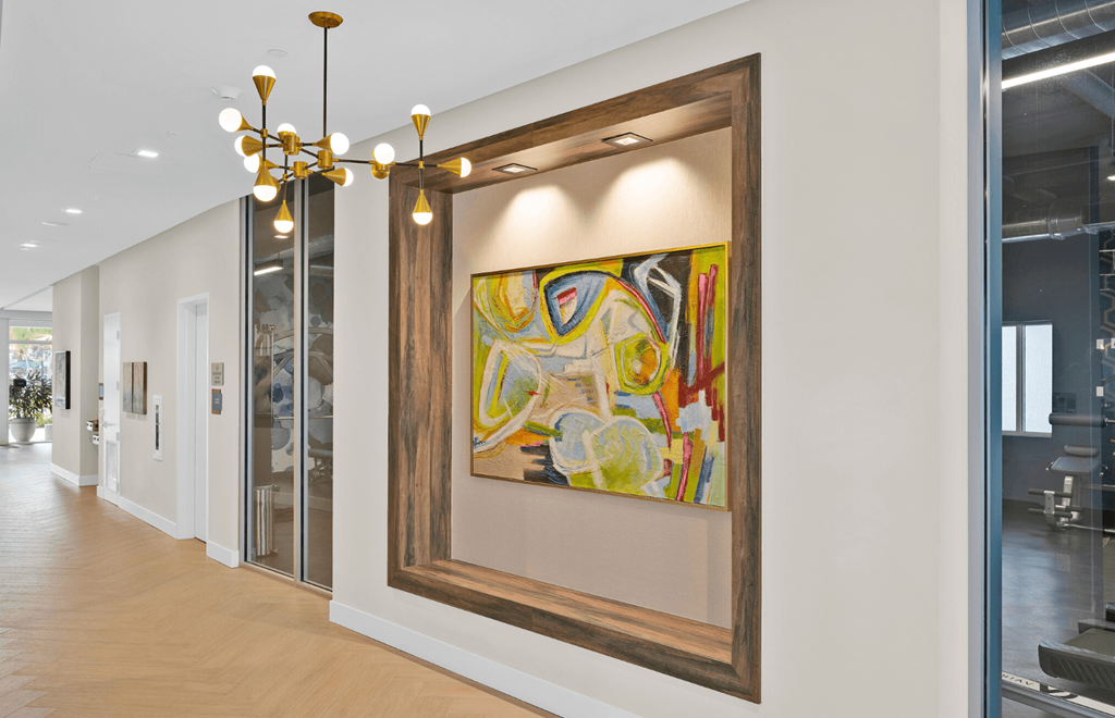 a large painting hangs on a wall in a hallway with a chandelier
