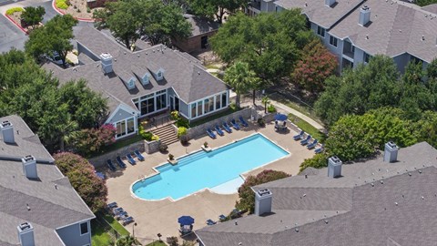 A swimming pool surrounded by a small building and trees.