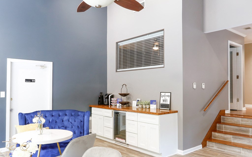 a living room with a blue couch and a kitchen with a counter and a window