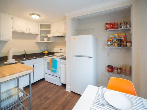 a kitchen with white appliances and a table and a refrigerator