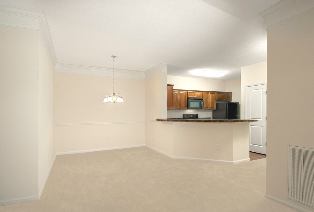 an empty living room with a kitchen and a counter top