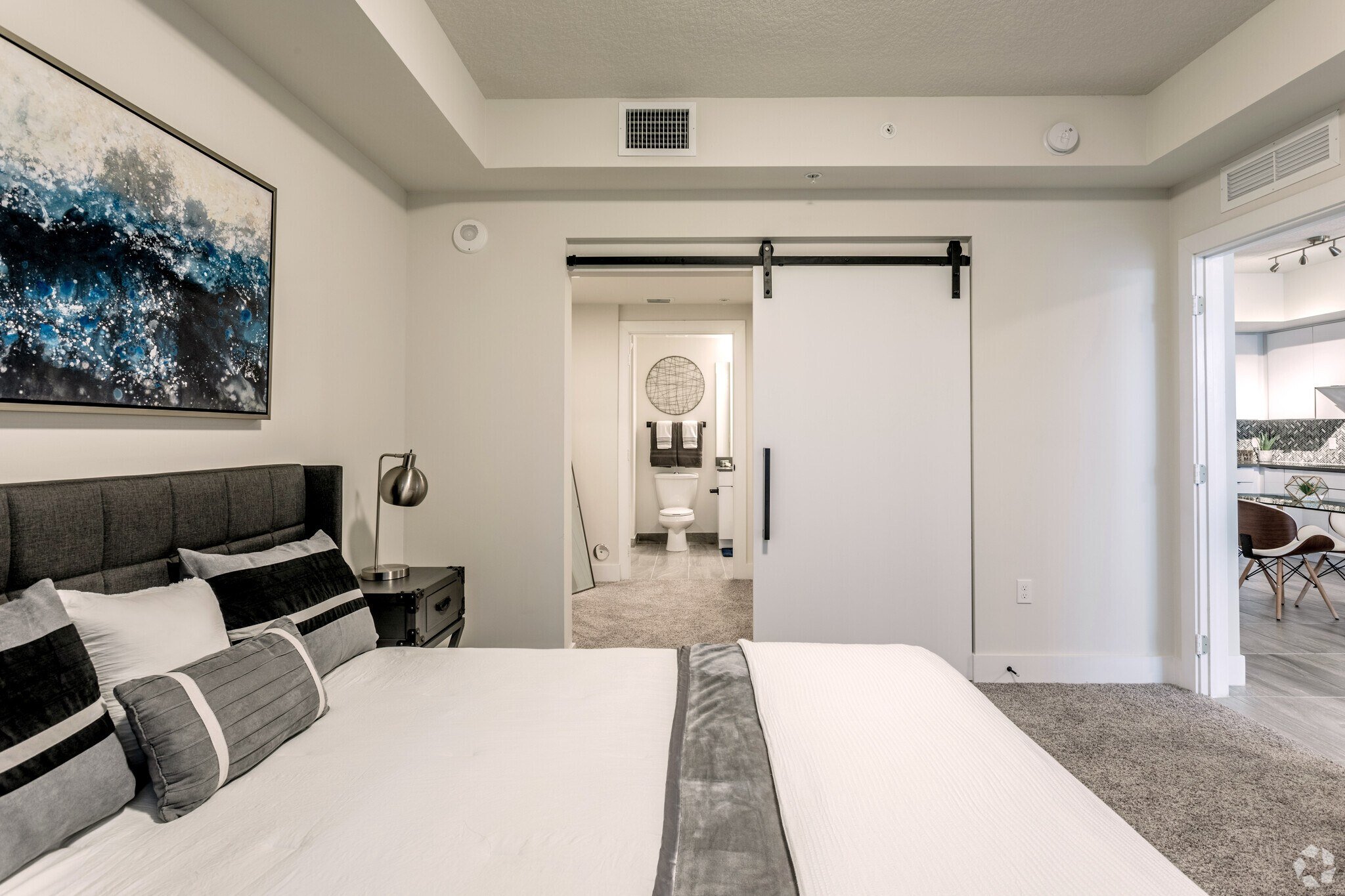 A bedroom with a large bed and a painting on the wall.