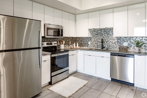 A modern kitchen with stainless steel appliances and white cabinets.