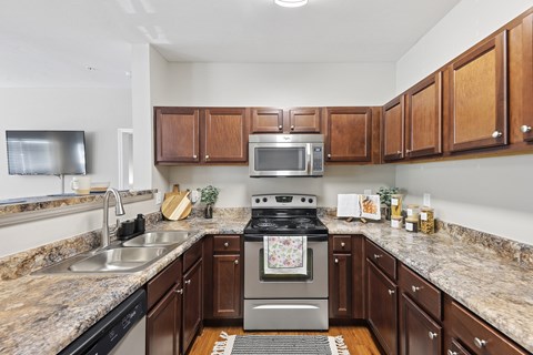 A kitchen with brown cabinets and granite countertops.