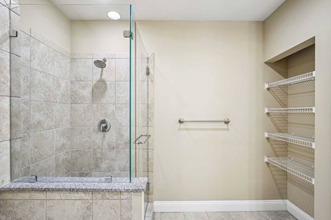 A walk-in shower with a glass door and a bench seat.