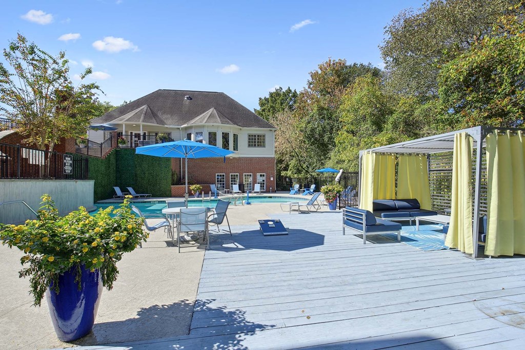 a backyard with a pool and patio with chairs and umbrellas