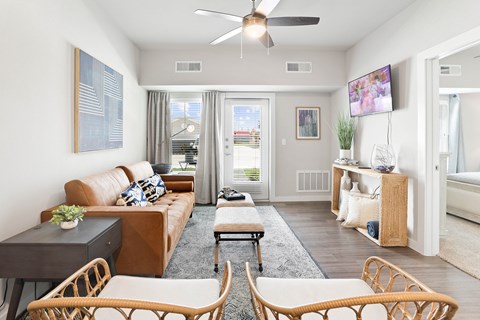 A living room with a brown couch and a ceiling fan.