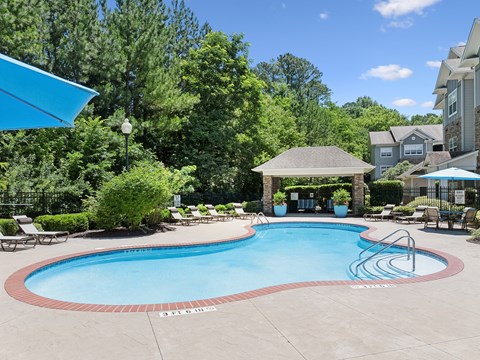 A swimming pool surrounded by trees and a gazebo.