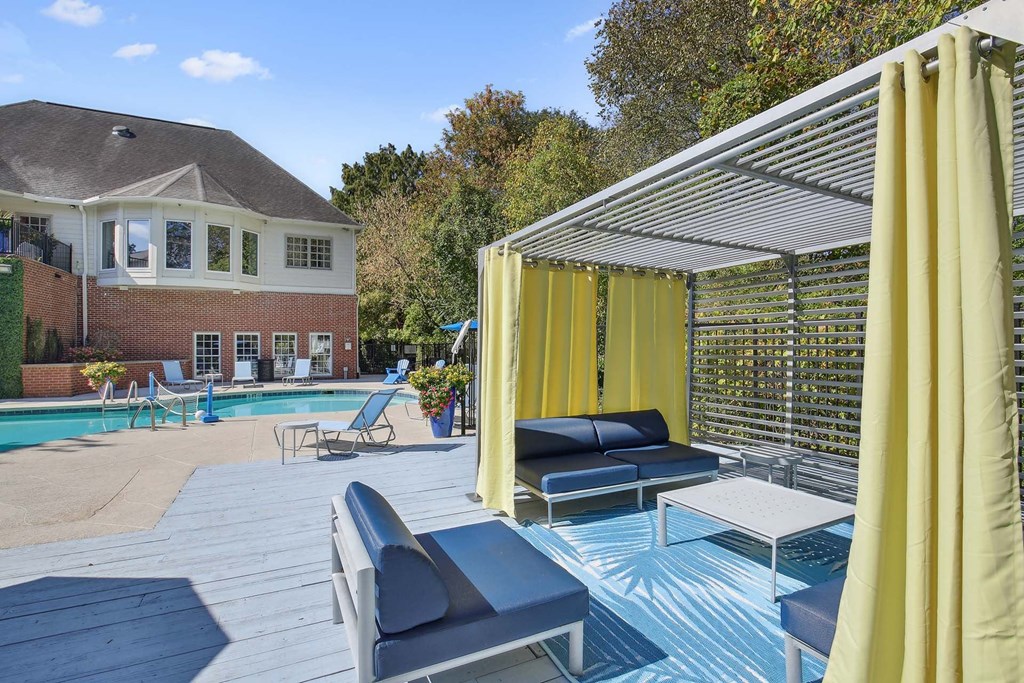 a pool with lounge chairs and umbrellas and a house in the background