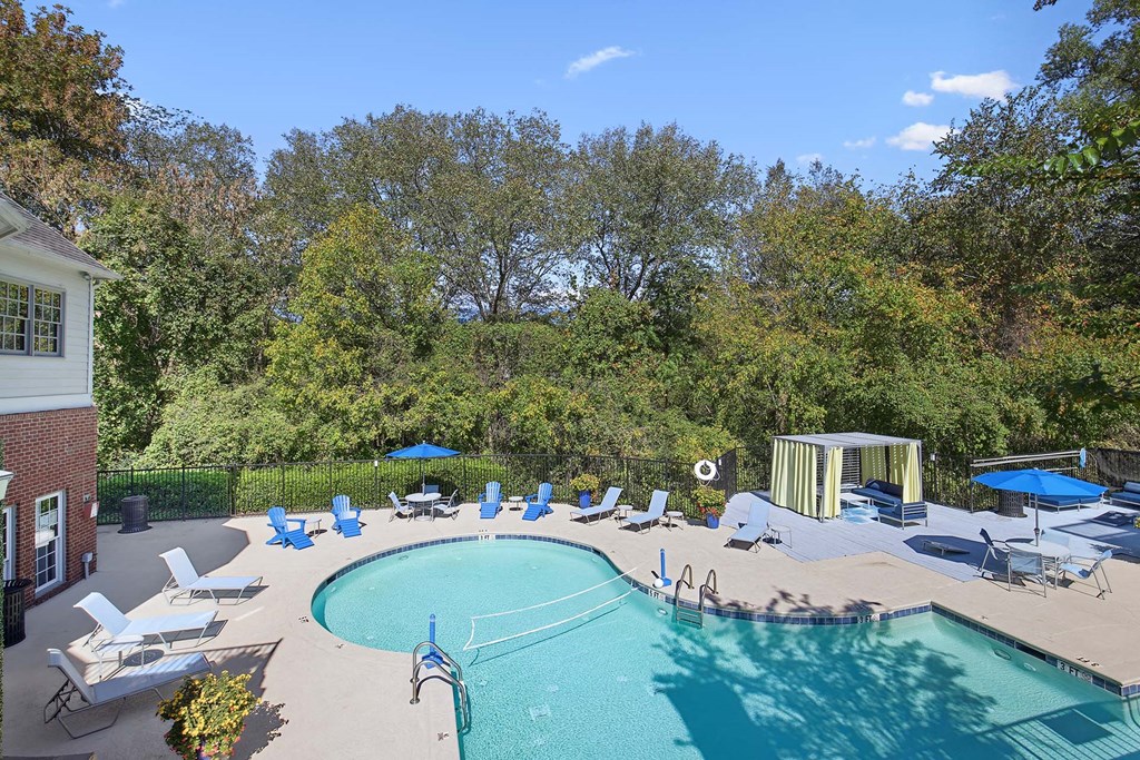 a swimming pool with chairs and umbrellas next to a house