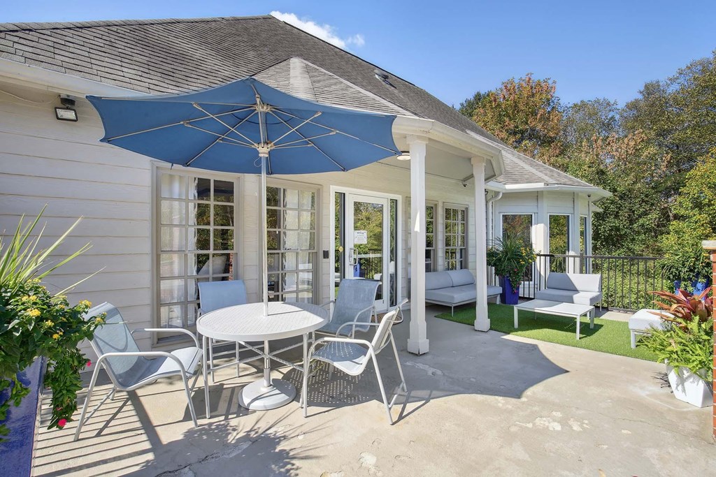 a patio with a table and chairs under an umbrella