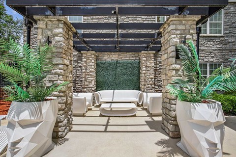 A patio with white chairs and a stone wall.
