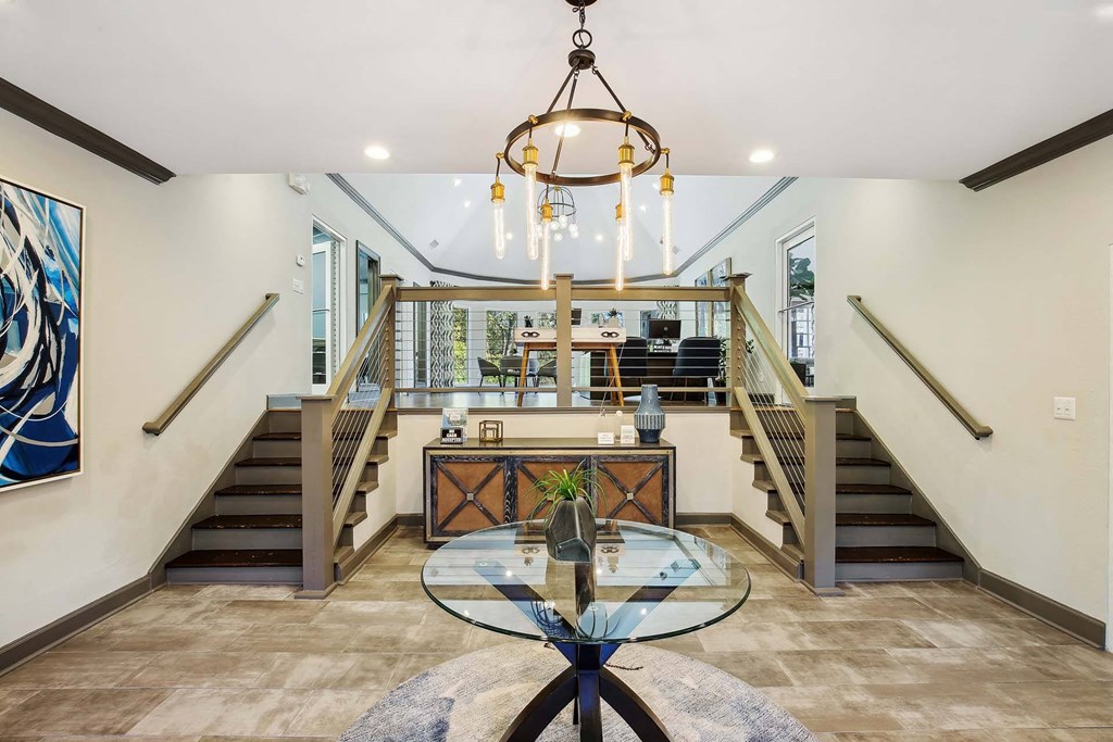 the entryway of a house with a glass table and stairs