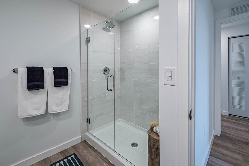 a bathroom with a glass shower and two towels on a rack at Altis Blue Lake, Lake Worth, Florida