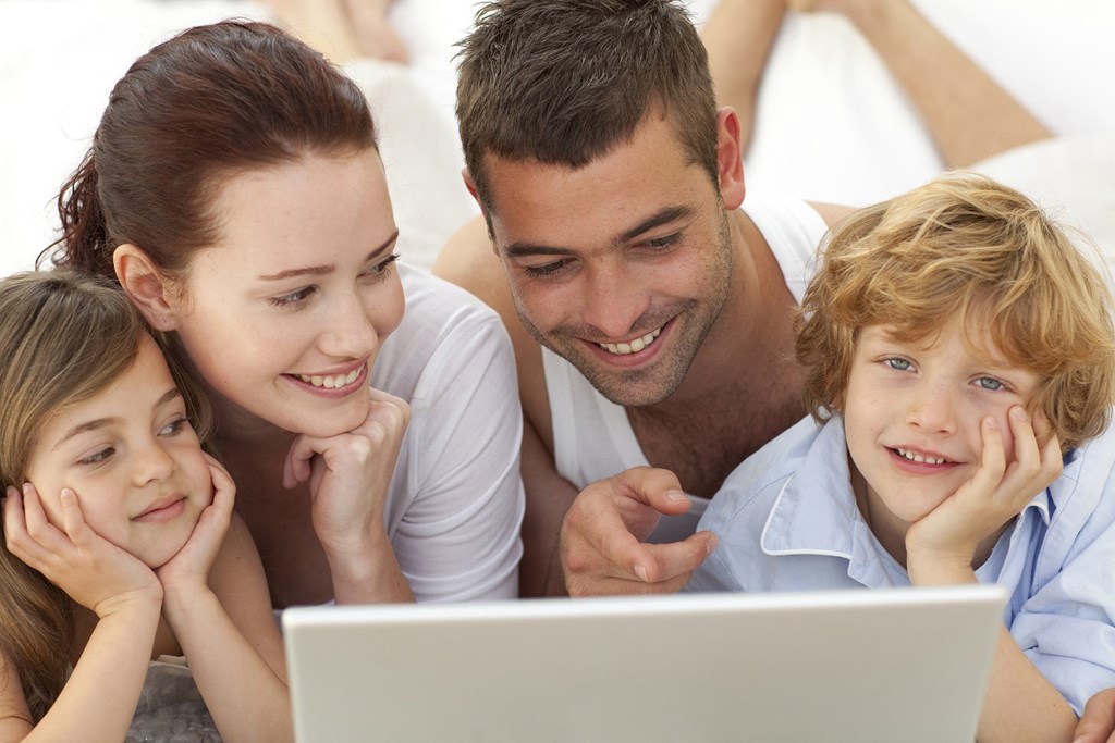 a family lying on the floor looking at a laptop
