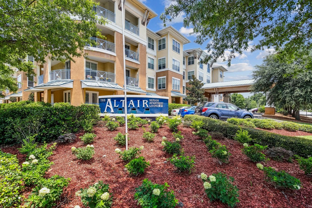 an apartment building with a sign in front of a garden
