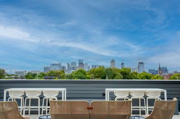 Four chairs are placed on a patio with a city skyline in the background.