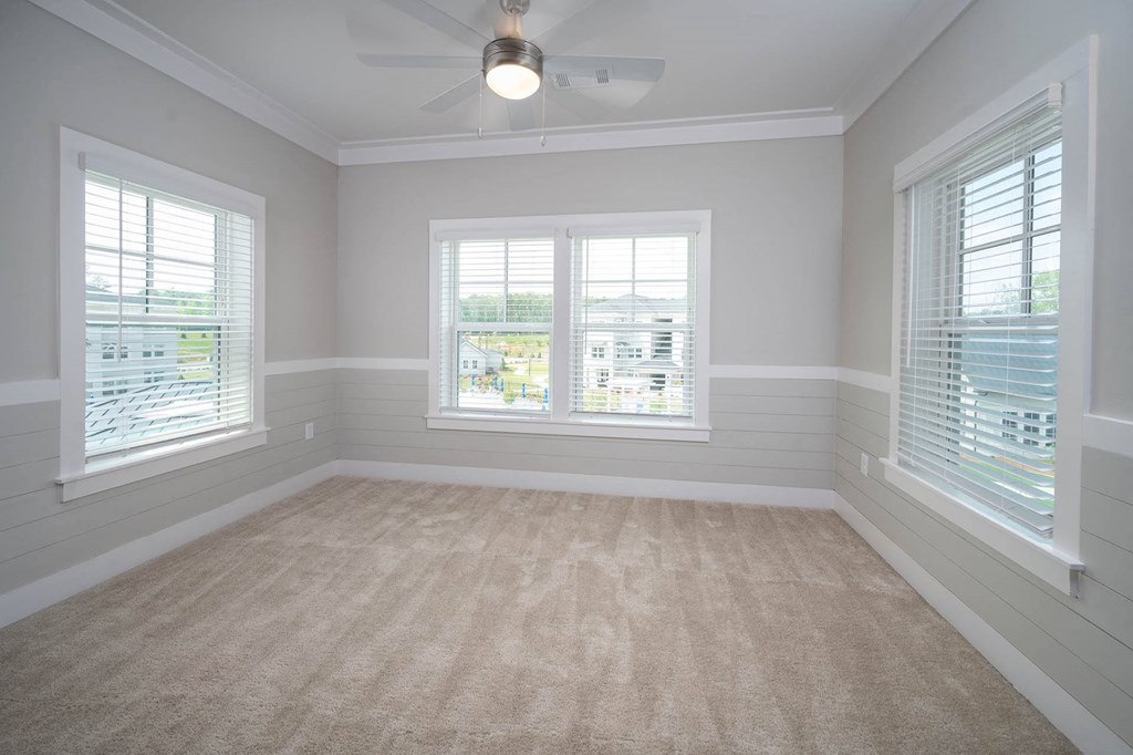 an empty room with three windows and a ceiling fan