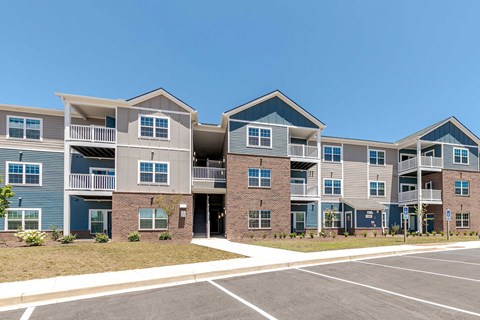 Apartment complex with a parking lot in front.