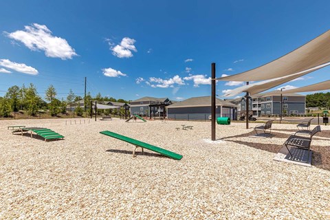 A playground with a green bench and a shade structure.