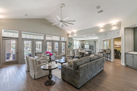 A spacious living room with a grey sofa, a round table with a flower on it, and a ceiling fan.