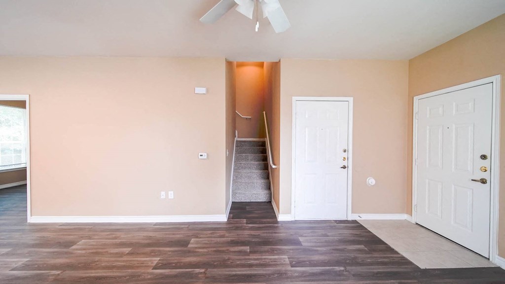 a living room with a door to a staircase and a ceiling fan
