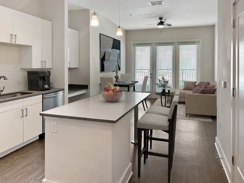 A kitchen with white cabinets and a large island with a bowl of fruit on it.