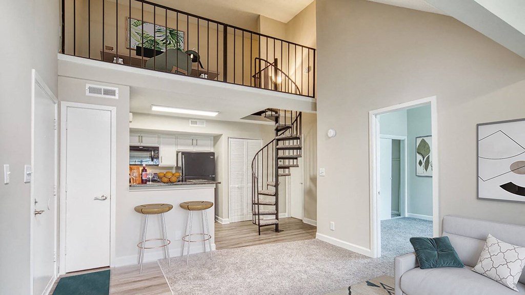 an open living room with a spiral staircase and a kitchen