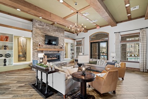 A living room with a stone fireplace and a chandelier.