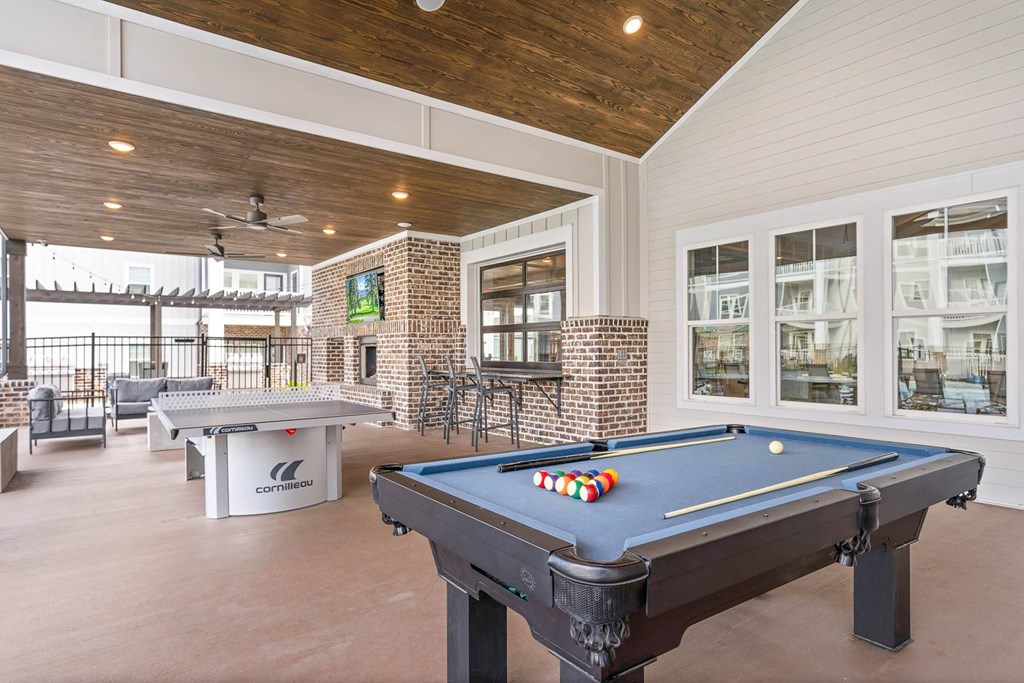 a covered patio with a pool table and a bar