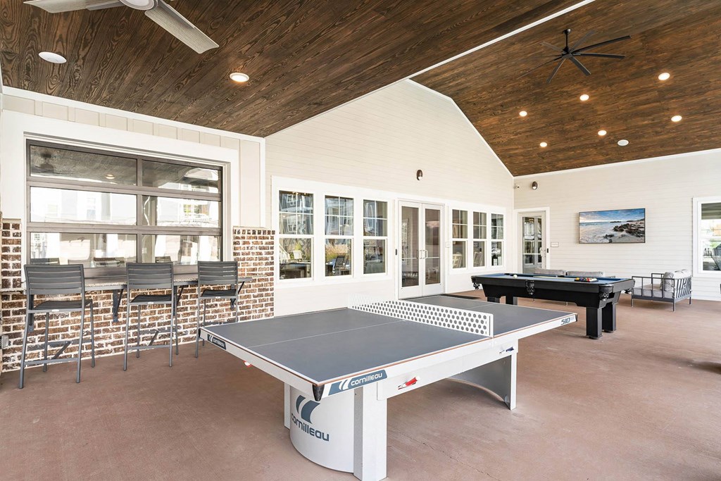 a game room with a ping pong table and chairs