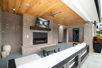 A modern outdoor patio with a fireplace and seating area.