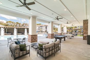 Outdoor beer garden styled with decorative lighting, private seating, fire pit, corn hole, and covered grilling stations