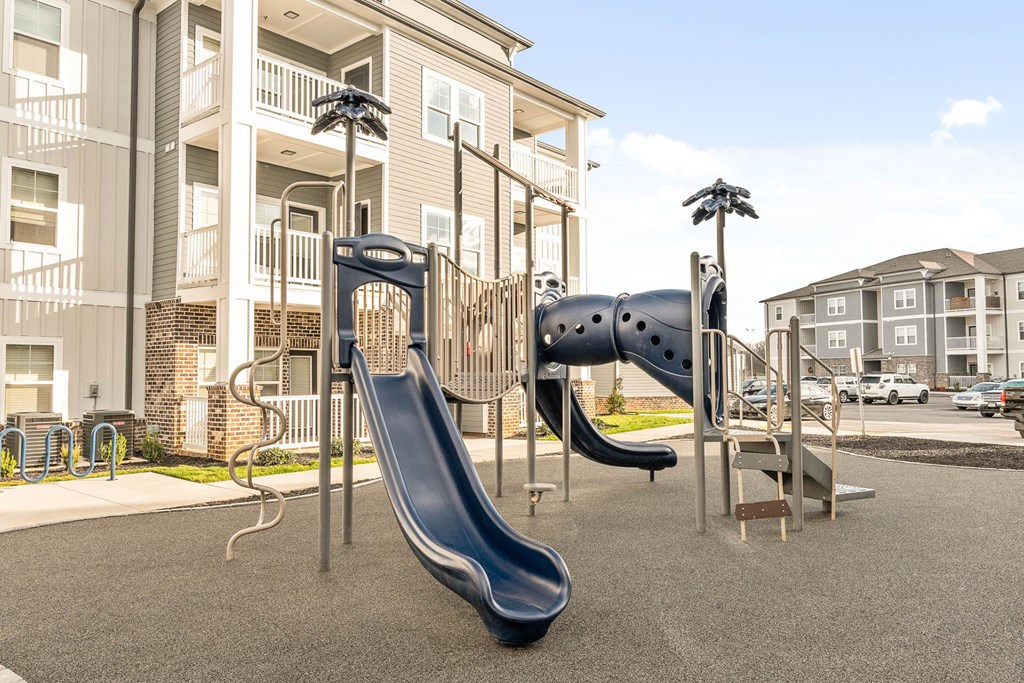 a playground with slides and climbing equipment in front of apartments