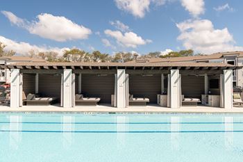 a swimming pool with lounge chairs and a building with a roof